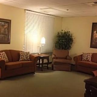 A cozy living room with sofas, an armchair, a lamp, and decorative elements.