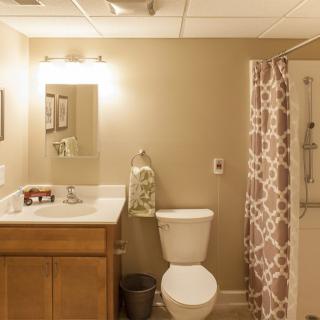 A well-lit bathroom featuring a sink, toilet, and patterned shower curtain.