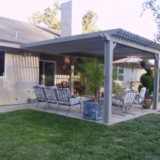 A backyard patio with a pergola providing shade over outdoor seating.