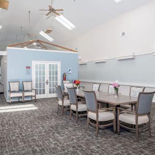 A spacious meeting room with a large conference table and several chairs, featuring bright lighting and elegant decor.