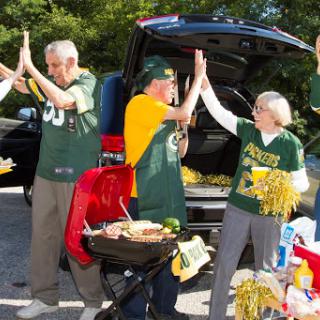 A lively group of fans celebrating a football game with tailgating festivities.