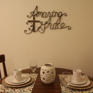 A cozy dining setup with elegant place settings and decorative wall art reading 'Amazing Grace'.