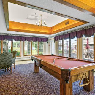 A spacious game room featuring a billiards table and large windows that invite natural light.