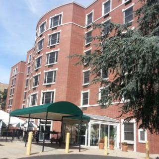 A multi-story brick apartment building with a green awning at the entrance.