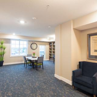 A well-lit room with a seating area, artwork, and a large clock on the wall.