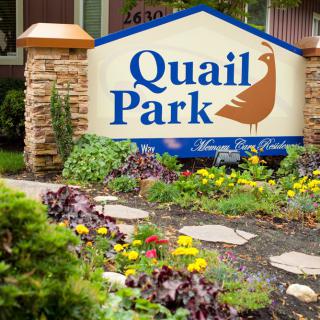 Entrance sign for Quail Park with well-maintained landscaping and a pathway.