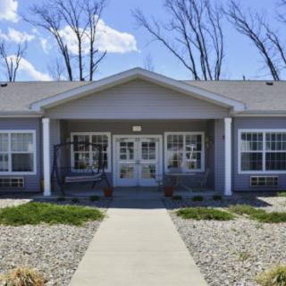 A single-story residential building with a front entrance and pathway under a clear blue sky.