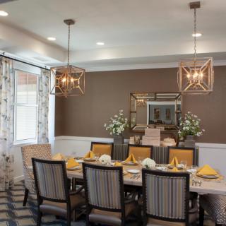 A modern dining room with stylish chandeliers, a large table setting, and elegant decor.