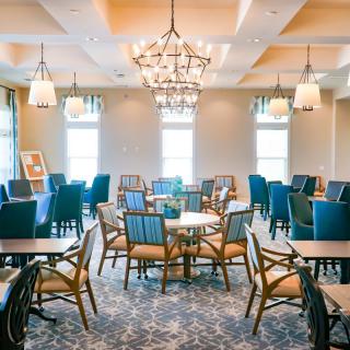 A well-lit dining area with stylish chairs, tables, and elegant chandeliers.