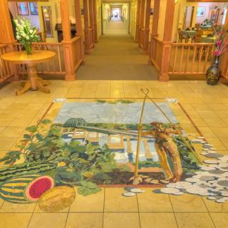 A hallway featuring a vibrant floor mural depicting a nature scene with watermelons and a river.