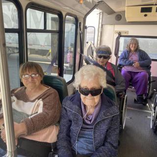 A group of seniors traveling on a bus, with one passenger in a wheelchair.