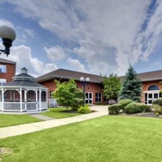 A well-maintained lawn with a gazebo and modern building under a partly cloudy sky.