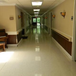 A clean, well-lit hallway inside a building with a piano on the left side.