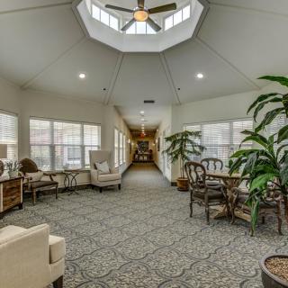 A spacious and well-lit interior living area with comfortable seating, greenery, and large windows.