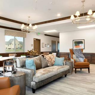 A well-decorated living room featuring a comfortable sofa, armchair, elegant chandeliers, and tasteful decor.