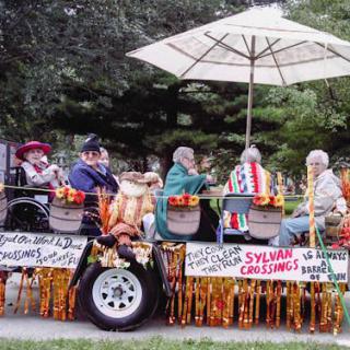 A decorated parade float carrying people under a large umbrella, adorned with festive ornaments.
