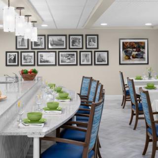 A modern dining room with neatly arranged tables and chairs, featuring framed wall art and elegant table settings.
