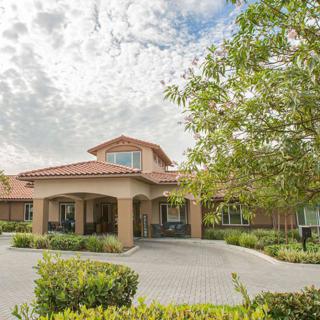 A residential building with a spacious driveway and lush landscaping under a cloudy sky.