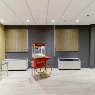 A popcorn machine in a modern indoor setting with neutral-colored walls and flooring.