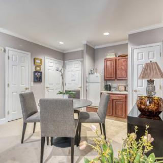 A modern dining area with a table and chairs adjacent to a compact kitchen.