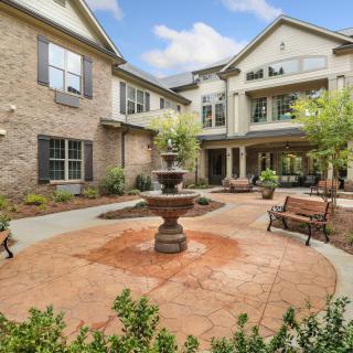 A serene courtyard featuring a central fountain surrounded by benches and well-maintained landscaping.