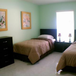 A cozy bedroom with twin beds, decorated with artwork and lamps on a shared nightstand.