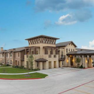 A modern residential building with a spacious driveway and clear sky.