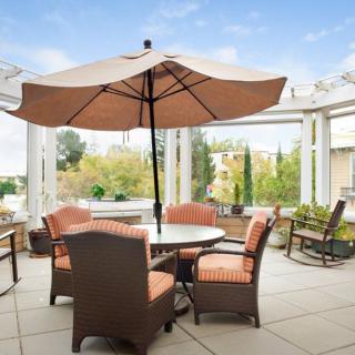 A cozy outdoor patio setting with a round table, chairs, and a large umbrella.