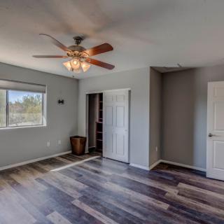 A spacious and well-lit room featuring modern flooring and a ceiling fan.