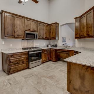 A modern kitchen featuring wooden cabinets and granite countertops with stainless steel appliances.