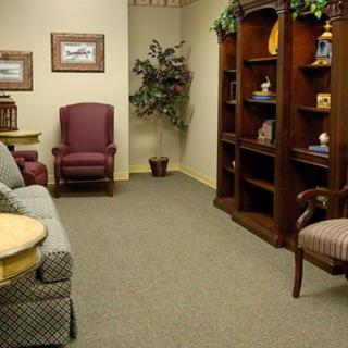 A cozy and inviting waiting room with comfortable seating and a well-organized bookshelf.