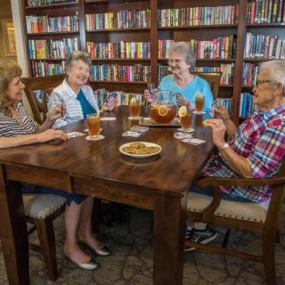 A group of seniors enjoying drinks and conversation in a cozy library setting.