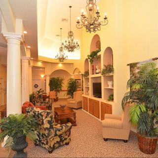 A cozy living room with elegant chandeliers, plush seating, and lush indoor plants.