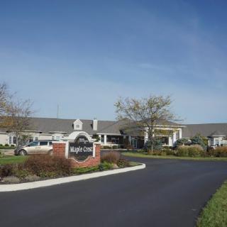 A large building with a driveway and sign in the foreground under a clear blue sky.