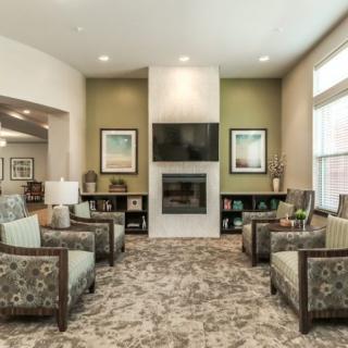 A cozy living room with modern decor featuring a central fireplace and comfortable seating.