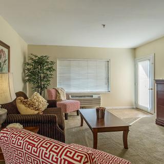 A cozy living room with a neutral color palette, featuring a sofa, armchair, coffee table, and decorative accents.