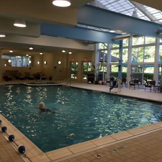 An indoor swimming pool with surrounding chairs and large windows.