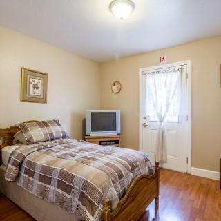 A cozy bedroom with a single bed, a television, and simple decor.