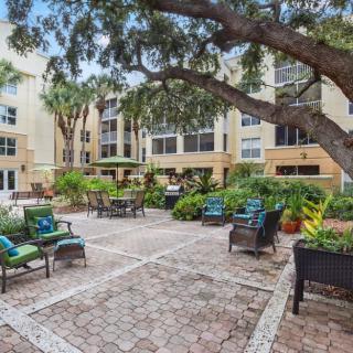 A serene courtyard with outdoor seating surrounded by lush greenery and apartment buildings.