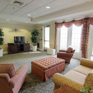 A cozy living room with comfortable seating, a television, and large windows allowing natural light to fill the space.