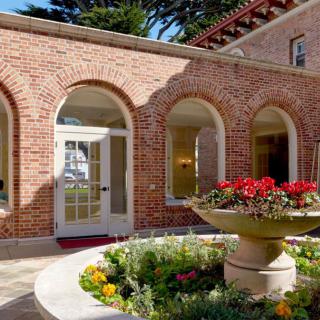 A charming courtyard with brick arches and a central fountain surrounded by vibrant flowers.