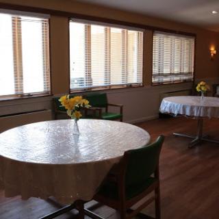 A serene dining space with neatly arranged tables and chairs, illuminated by natural light.