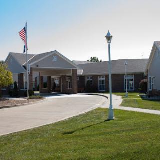A welcoming healthcare facility with an American flag and landscaped grounds.