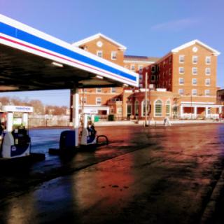 A gas station with an adjacent building under clear blue skies.