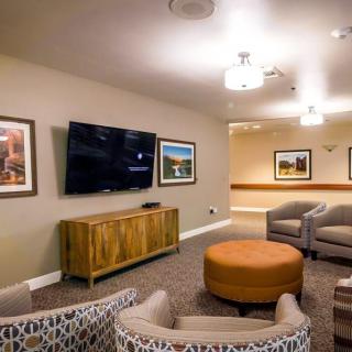 A modern living room with a large television, comfortable seating, and decorative artwork on the walls.