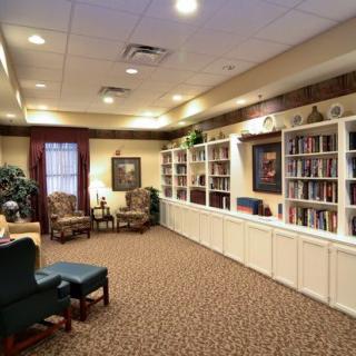 A cozy library room featuring wall-to-wall bookshelves, comfortable seating, and a warm atmosphere.