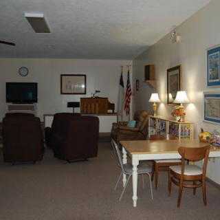 A cozy community room featuring comfortable seating, a table, and a television.