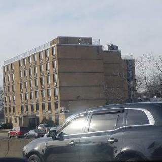 A view of a building alongside a busy highway, with a car in the foreground.