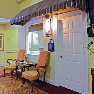 A cozy interior space with a waiting area featuring two chairs, a small table, an awning above a window, and a door.