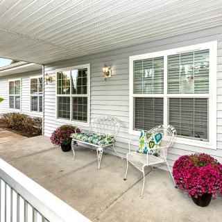 A cozy porch area with seating and colorful potted flowers.